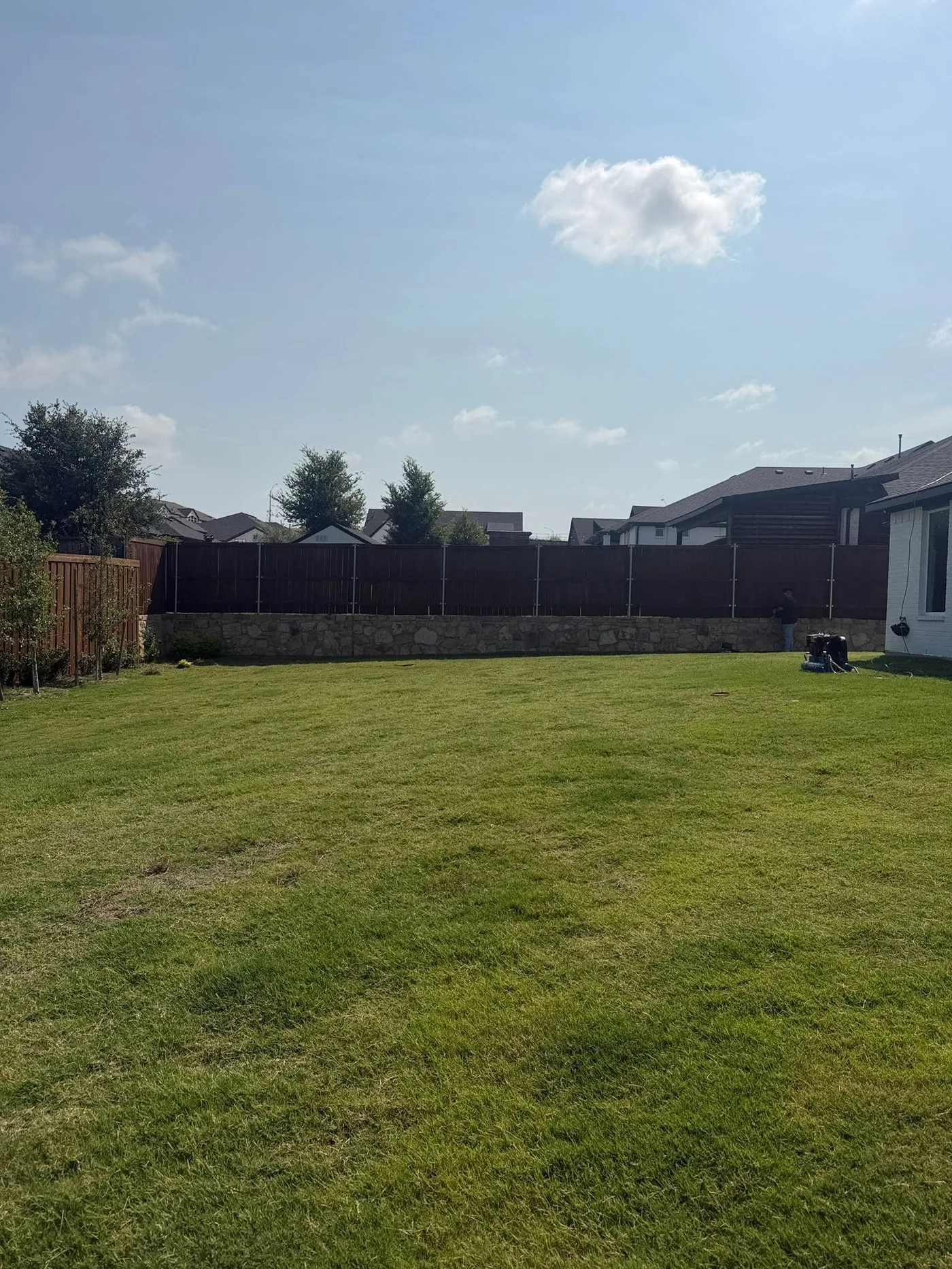 New wood privacy fence along a backyard with stone base
