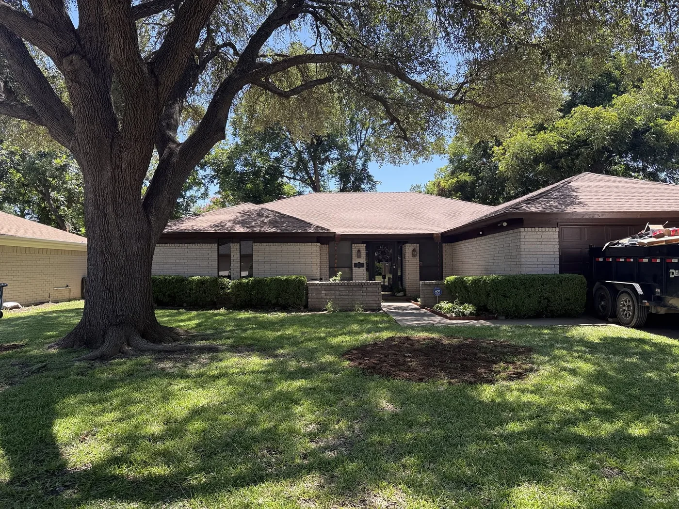 Ranch-style home with new roof under large oak trees